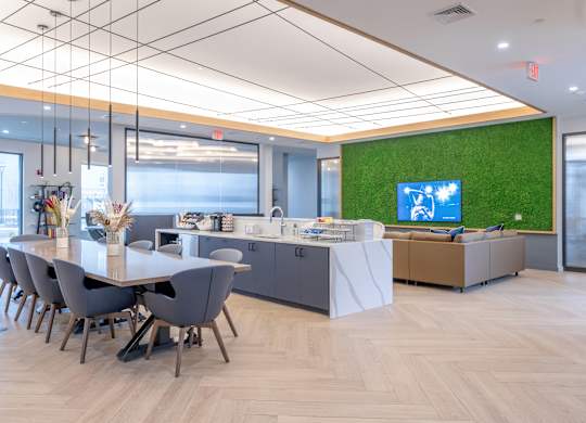 A conference room with a long table and chairs, a reception desk, and a green wall with a TV at Seacoast Residences Apartments, Oakland, ME
