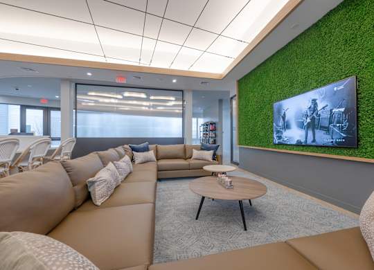 A modern living room with a green wall and a large screen TV at Seacoast Residences Apartments, Oakland