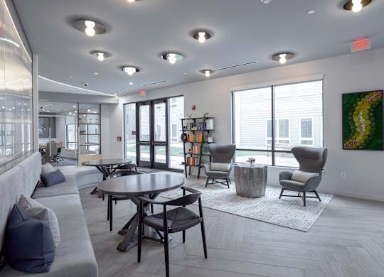A modern living room with a grey sofa, a round table, and a painting on the wall at Seacoast Residences Apartments, Oakland, ME