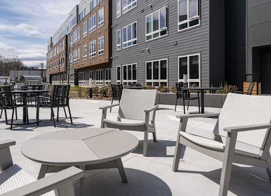 A patio with a table and chairs is in front of a building at Seacoast Residences Apartments, Maine