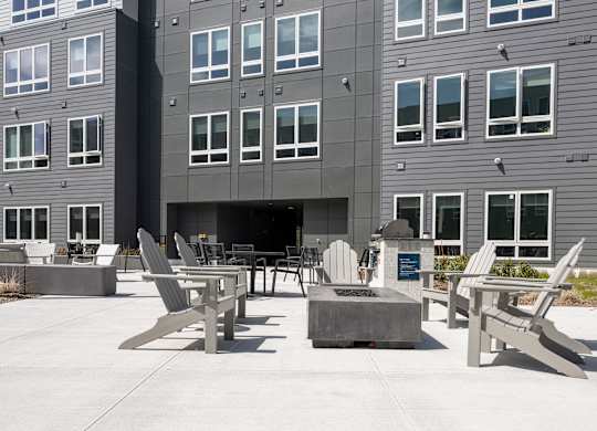 A grey building with a patio area in front at Seacoast Residences Apartments, Oakland