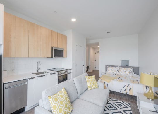 a living room with a couch and a kitchen and a bed