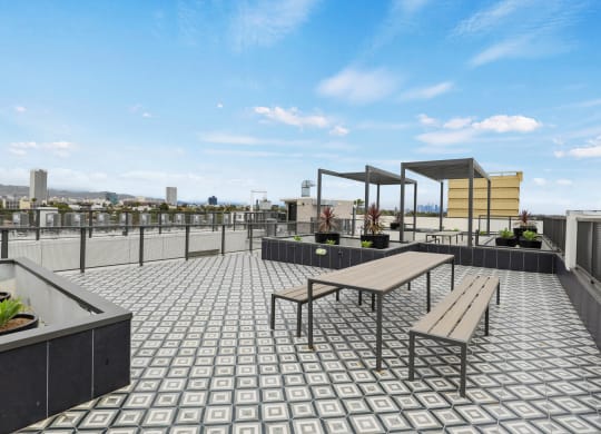 a roof deck with a picnic table and benches at The Fairfax Flats Apartments, Los Angeles, California