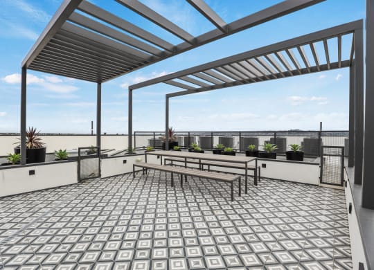 a view of the rooftop terrace of a building with a pergola and benches at The Fairfax Flats Apartments, Los Angeles, CA, 90019