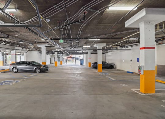 a parking garage with two cars parked on the left and one car on the right at The Fairfax Flats Apartments, Los Angeles, California