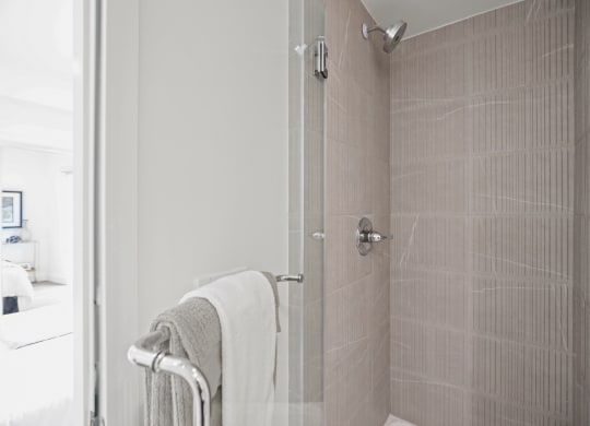 a bathroom with a shower and a towel rack at The Fairfax Flats Apartments, Los Angeles, CA