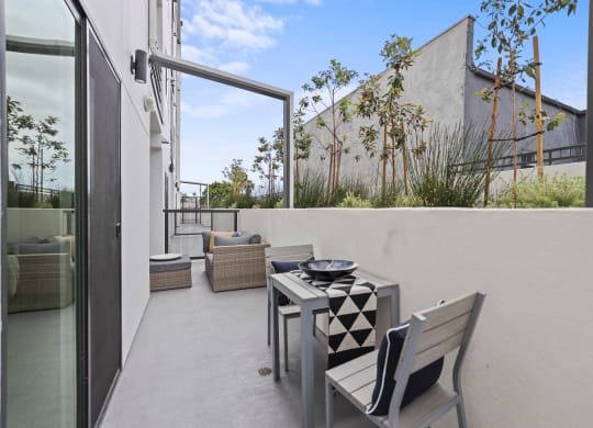 a small balcony with a table and chairs at The Fairfax Flats Apartments, Los Angeles, California