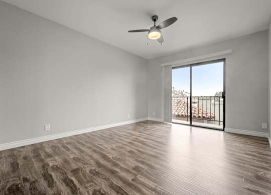 A room with a ceiling fan and sliding glass doors leading to a balcony at Lafayette Apartments, Los Angeles