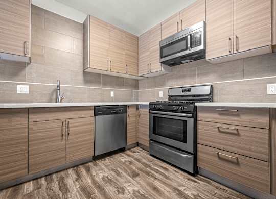 A kitchen with wooden cabinets and black appliances at Lafayette Apartments, Los Angeles