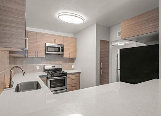 A modern kitchen with a sink, stove, and microwave at Lafayette Apartments, Los Angeles, CA