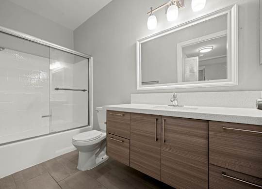 A bathroom with a toilet, sink, and mirror at Lafayette Apartments, California