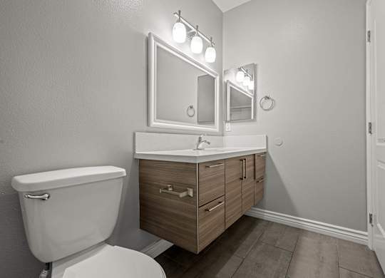 A bathroom with a toilet, sink, and mirror at Lafayette Apartments, Los Angeles 90019