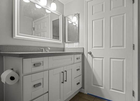 A bathroom with a white door and a mirror above it at Lafayette Apartments, Los Angeles, CA