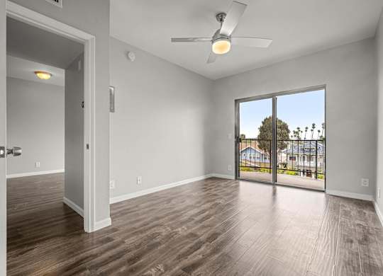 A room with a ceiling fan and sliding glass doors leading to a balcony at Lafayette Apartments, Los Angeles, CA, 90019