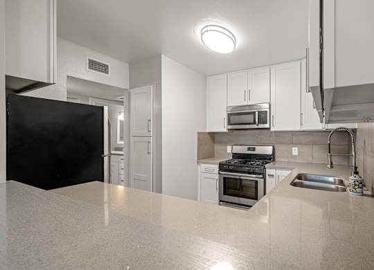 A kitchen with white cabinets and stainless steel appliances at Lafayette Apartments, Los Angeles, California