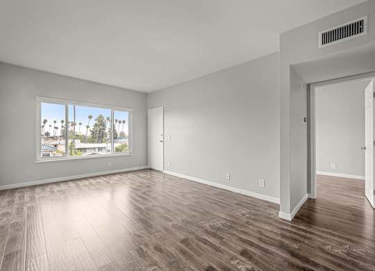 A room with wooden flooring and a large window overlooking a cityscape at Lafayette Apartments, Los Angeles, CA
