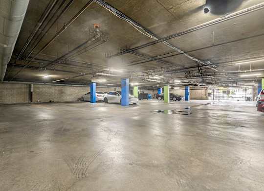 A parking garage with a concrete floor and multiple cars parked at Lafayette Apartments, California, 90019