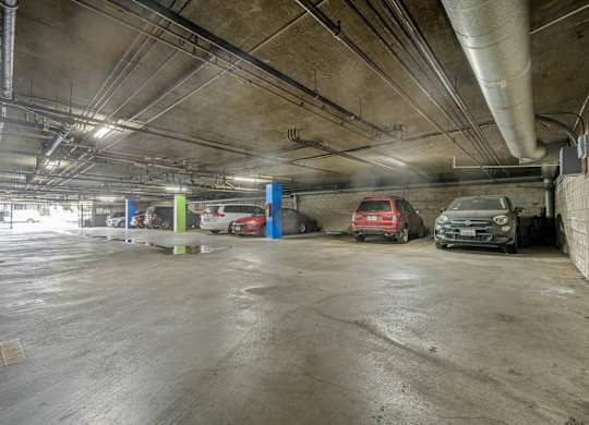 A parking garage with a few cars and a blue wall at Lafayette Apartments, Los Angeles, California