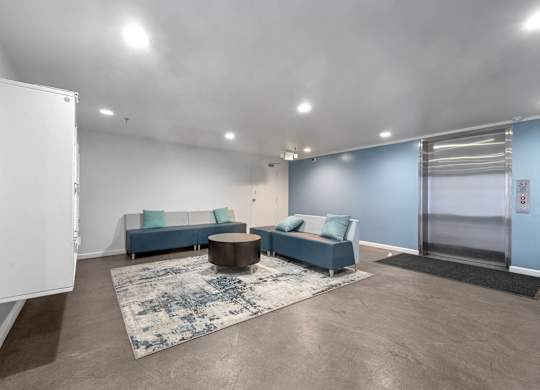 A spacious living room with a blue sofa and a coffee table at Lafayette Apartments, Los Angeles, CA