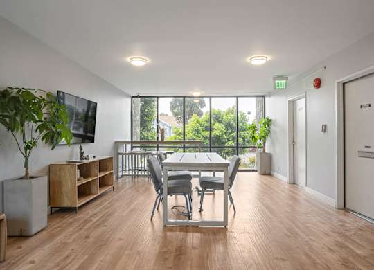 A room with a wooden floor and a large window with a view of trees at Lafayette Apartments, California, 90019