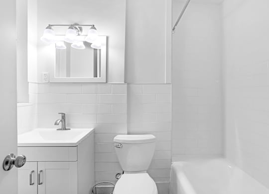 A white bathroom with a toilet, sink, and mirror.at Park Wilshire, California, 90057