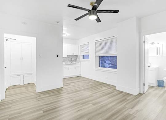 A room with a ceiling fan and light, wooden floors, and a window with blinds.at Park Wilshire, Los Angeles, 90057