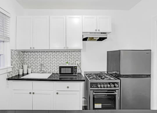 A kitchen with white cabinets and a black stove top.at Park Wilshire, California