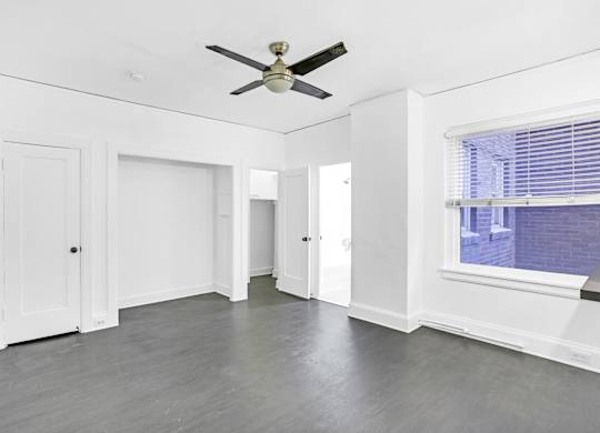 A room with a ceiling fan and a window with blinds.at Park Wilshire, Los Angeles