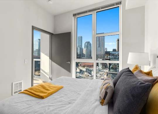 A bedroom with a large bed and a view of the city through the window.