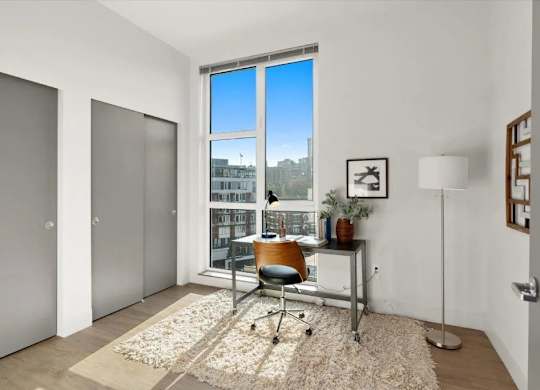 A room with a desk and a chair in front of a window with a view of a cityscape.