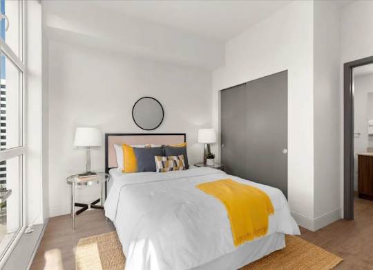 A bedroom with a white bed and yellow throw.