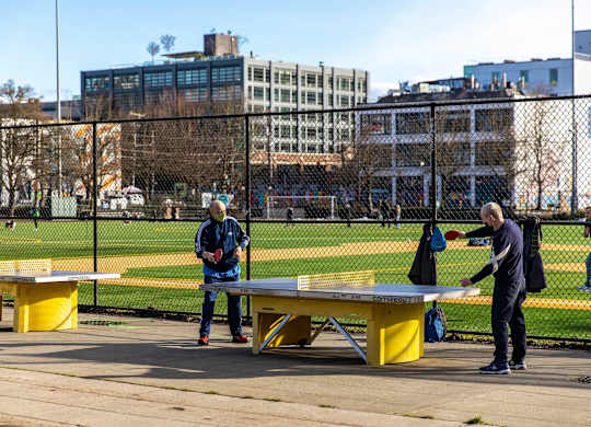 Two men playing ping pong in a park.