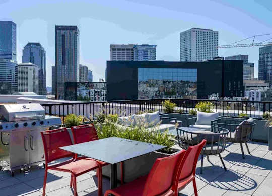 A rooftop patio with a table and chairs overlooking a city skyline.