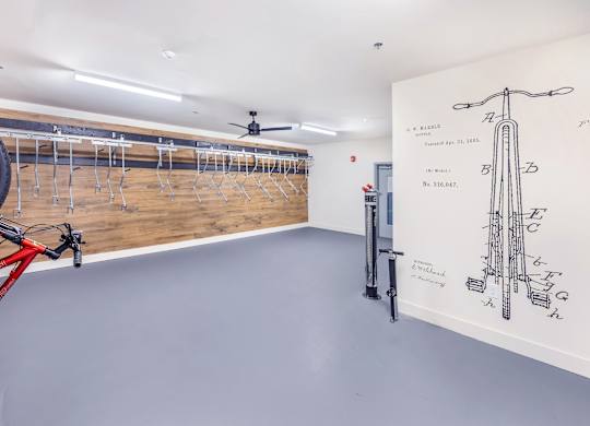 A bike is parked in a room with a wall drawing of a bike.