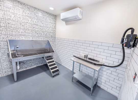 A kitchen with a stainless steel sink and a white tile wall.