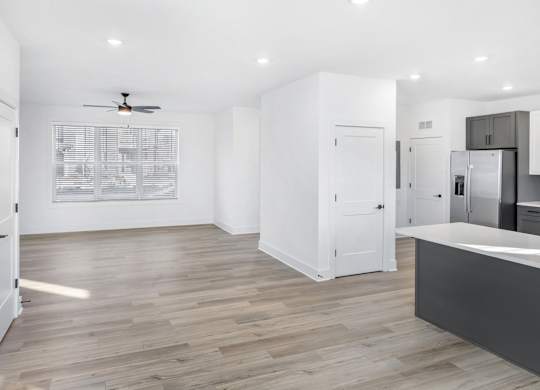 A spacious kitchen with a ceiling fan and wooden flooring.