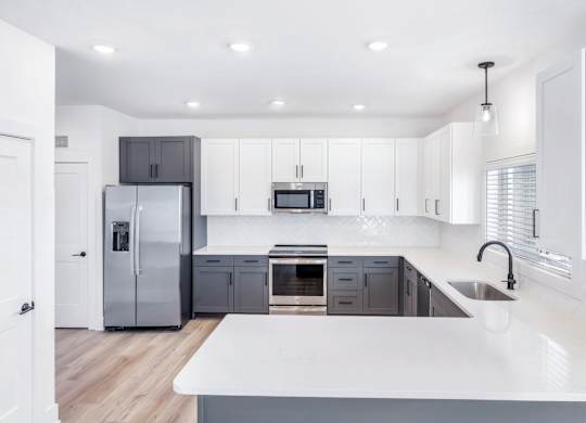 A modern kitchen with a white countertop and stainless steel appliances.