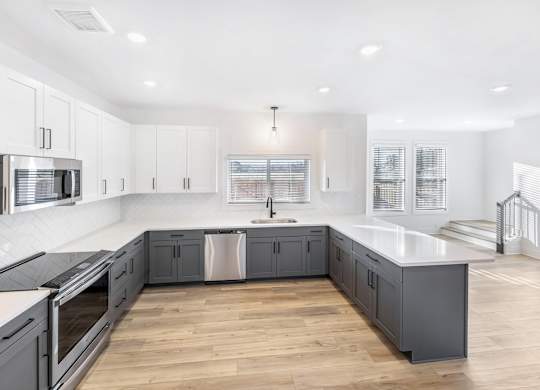 A modern kitchen with wooden floors and white cabinetry.