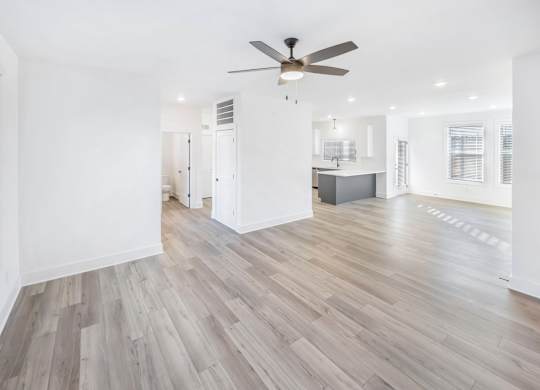 A room with a ceiling fan and wooden flooring.