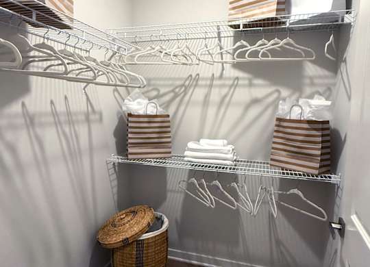 A laundry room with a basket and clothes on the shelves.
