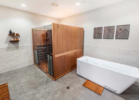 A modern bathroom with a white tub and wooden shower.