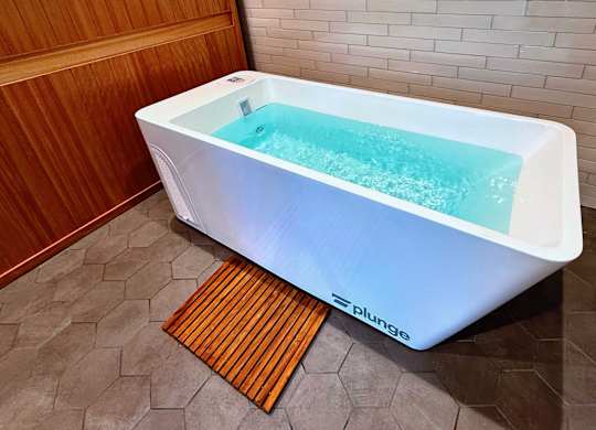 A white hot tub with a blue interior is on a tiled floor in a bathroom.