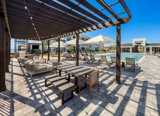 A patio with a table and chairs under a wooden pergola.