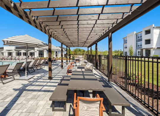 A sunny day at the poolside with loungers and tables.