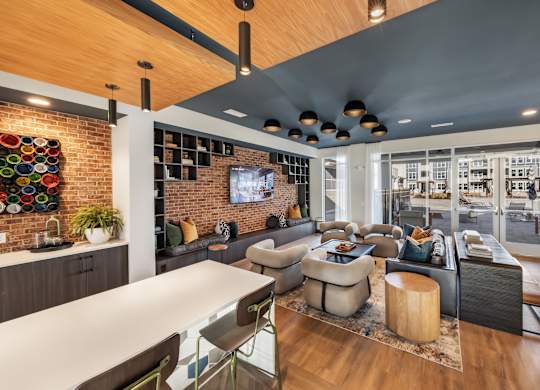 A modern living room with a brick wall and a long white table.