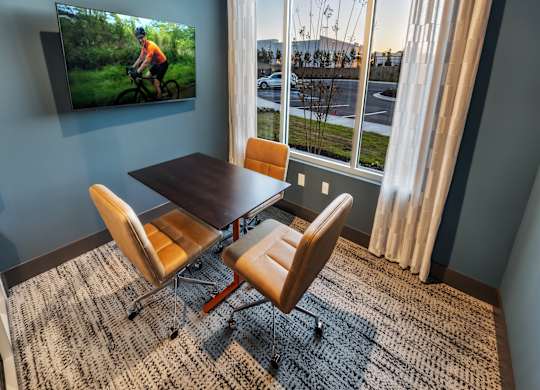 A room with a table and chairs and a TV mounted on the wall.
