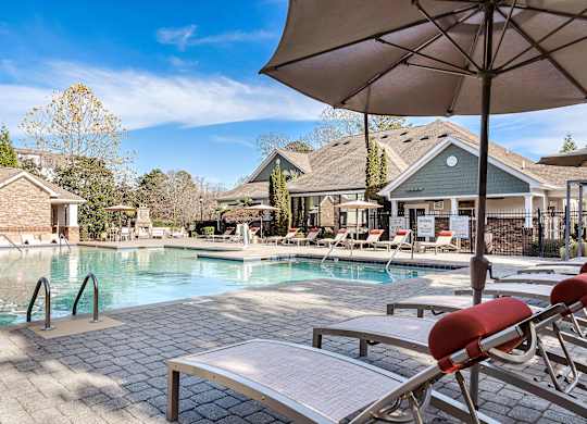 A pool with a bench and an umbrella in front of a house at Echo at Lake Norman, Mooresville