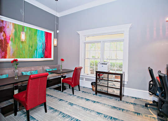 A room with a red chair and a painting on the wall.