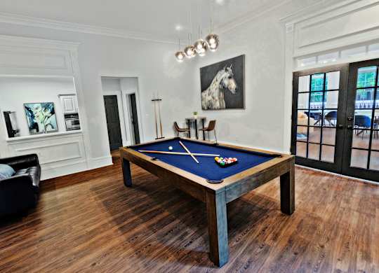 A pool table in a room with a horse painting on the wall.