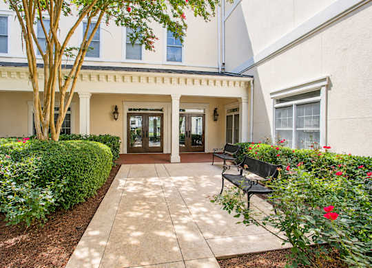 A building entrance with a bench and a tree.